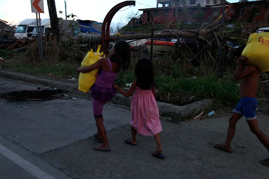 CHILDREN head home after getting food packs from a government aid station in Tacloban City. | Photo by Julius D. Mariveles
