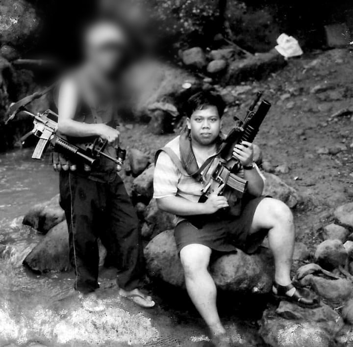 The author holds an AR15 with a grenade launcher borrowed from the NPA as one of its Red fighters pose with him for posterity. | Photo from Julius Mariveles personal collection