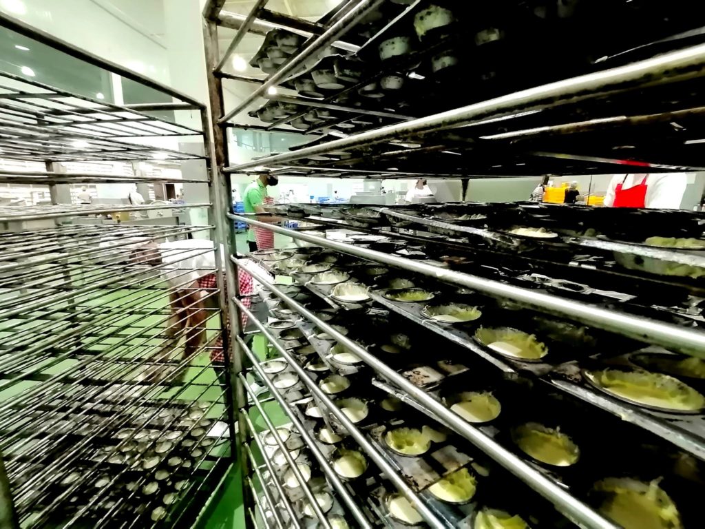 A baker loads molds filled with dough of toasted mamon (Filipino sponge cake) on stainless steel trolleys that will bring these straight to the ovens inside a modern production facility in Vista Alegre village in Bacolod City, Philippines. This facility produces pasalubong products by Merzci, one of the biggest brands based in Bacolod.