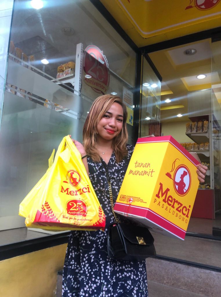 DNX reporter Nikki Magbanua takes photo at Merzci Homesite factory show room with her pasalubong from Bacolod packs.