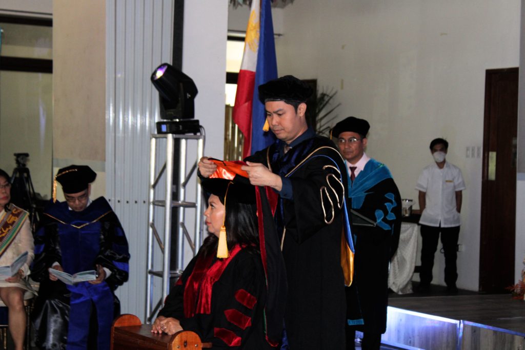 College of Arts and Sciences Dean Arjay Alvarado, PhD, DPA, places the academic hood on one of the graduates during the Hooding Ceremony.