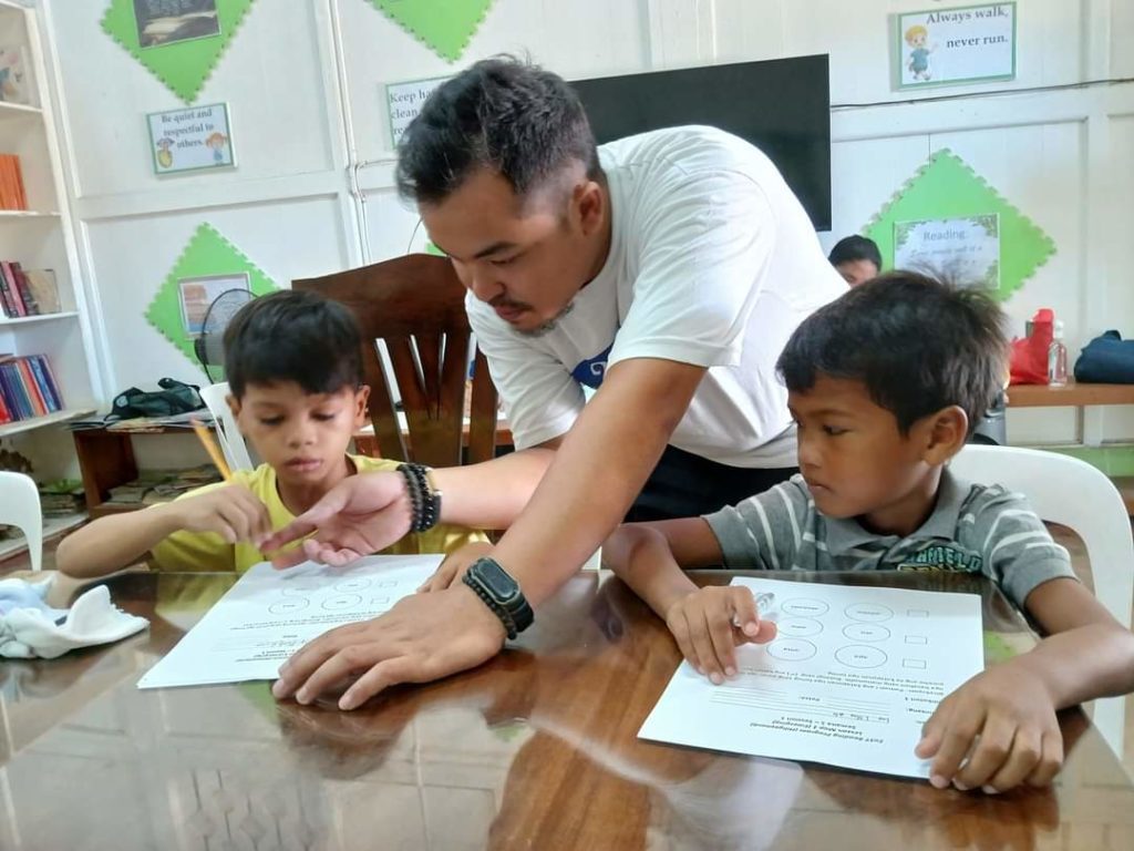 A VMC employee gives reading tutorial to schoolchildren as part of their "Catch-up Fridays" program to improve reading comprehension.